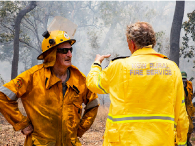 Two fire fighters talking near burnt out area